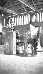Woman in wash house with pitcher pump :