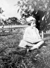 Virginia Ahern reading beside a young citrus tree - Babson Park, Florida