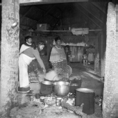 Seminole women standing in front of several cooking pots