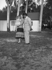 Woman holding little girl standing with man in open area