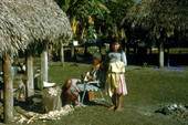 Young Seminole Indian girl by Charlie Cypress as he whittles wood