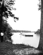 Man at Torreya State Park photographing a barge on the Apalachicola River