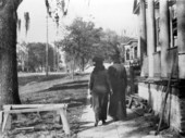 Two people walking along a sidewalk in Tallahassee.