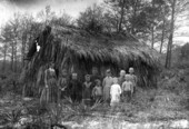 Class assembled in front of a thatched one-room school building