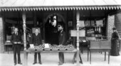 Men standing by apples in front of Tibbetts Brothers confectionery - Tampa, Florida.