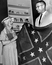 Secretary of State Tom Adams holding up Confederate Army battle flag with Mrs. E.A. Hayden - Tallahassee, Florida.