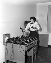 Mrs. Red Taylor with a desk covered with telephones.