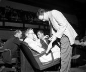 Men in legislature in a discussion at their desk