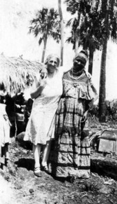 Unidentified midwife standing with Susie Tiger at a temporary camp in Immokalee, Florida.