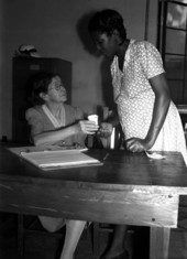 Nurse providing cup to expectant mother for urine sample.