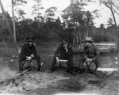 Men in uniforms sitting at a quarantined isolation camp.
