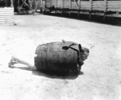 Man wearing barrel restraint while lying on ground.