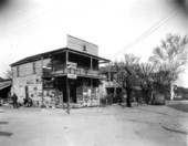 African American men sitting in front of a grocery store.