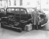 Man standing with a truck and luggage.