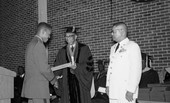 FAMU president Dr. George W. Gore presenting award to new graduate during commencement at Gaither Gymnasium in Tallahassee.
