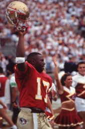 FSU quarterback Charlie Ward holding up his helmet on the sideline during a home game in Tallahassee, Florida.