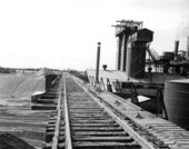 High stacks of phosphate form shoulders for elevated railroad at IMC.