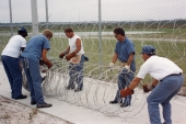 Inmates putting up razor wire with the guidance of a corrections officer at the Columbia Correctional Institution.