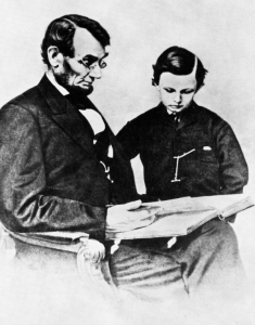 Picture postcard of President Abraham Lincoln and his son Tad looking at a large photographic album.